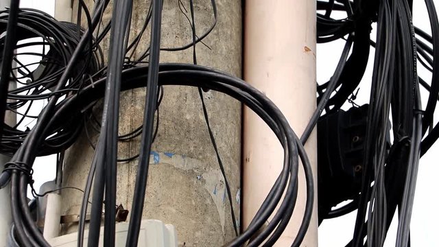 Clock with many electrical cable and telephone line on electricity post, Saigon, Vietnam. Messy wires attached to the electric mast.