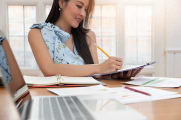 Freelancer business woman holding pen while working with business chart in cafe.