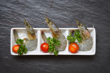 Fresh shrimps prawns raw seafood in cup ocean gourmet with tomato lemon and green parsley on dark background