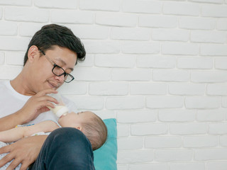 asian father  feeding milk to baby girl at home.