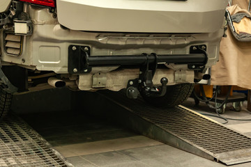 Close-up on a new black tow hitch installed on a modern car with a beige-colored bumper removed in...