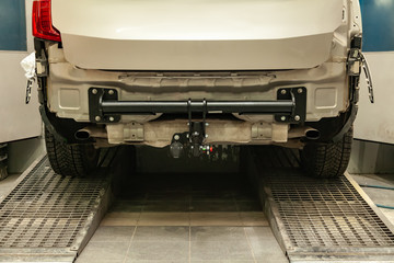 Close-up on a new black tow hitch installed on a modern car with a beige-colored bumper removed in...