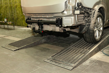 Close-up on a new black tow hitch installed on a modern car with a beige-colored bumper removed in...