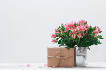Bunch of roses in tin bucket, petals and gift box on white wooden table. Women day concept. Rough string, craft wrap, vintage, 8 march, birthday, anniversary, spring