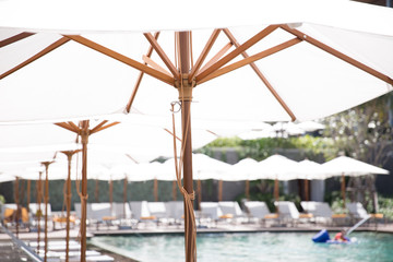 Fototapeta na wymiar White vintage umbrella at the pool side of the 5-star resort hotel.