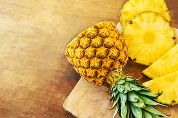 Pineapple on wood texture background. Whole and sliced tropical pineapple on wooden cutting board ...