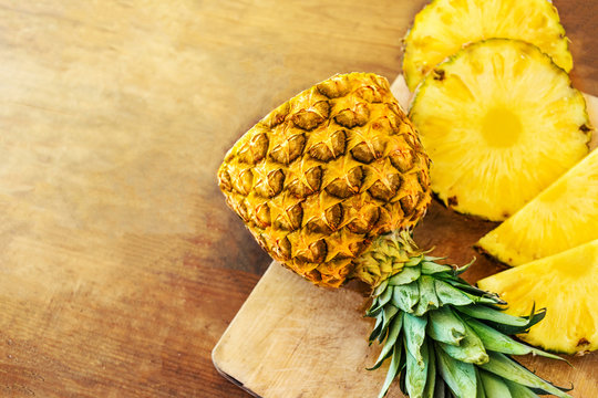 Pineapple on wood texture background. Whole and sliced tropical pineapple on wooden cutting board  with copy space. Top view.
