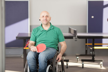 Fototapeta na wymiar Wheelchair user in the gym with a tennis racket in their hands. Rehabilitation of the disabled. Sport and a healthy lifestyle. Paralympic sports.