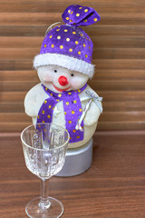 Toy snowman looks at an empty glass, close-up