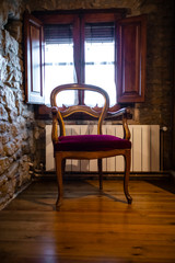 Old empty sitting chair on an interior old cobble stone house