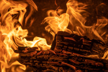 Flames shaping over dark firewood being burned