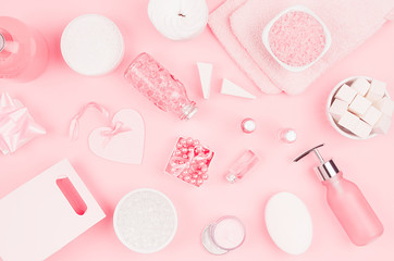 Cosmetic products for bathroom, health and hygiene in modern girlish style - decorative heart, soap, bath salt, essential oil, cream, towel, perfume, pearls, gift box on pink background.