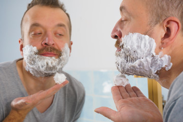 Guy shaving his beard in bathroom
