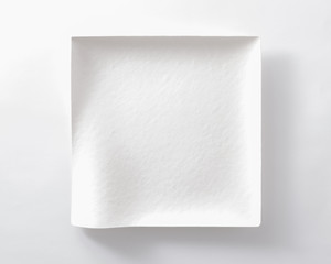 a square plate made of paper with curved lines. unique dish.