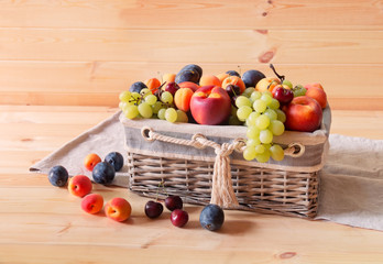 Wicker basket with fresh fruits on wooden table.
