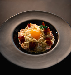 spaghetti carbonara egg On a black plate spaghetti carbonara egg  On a black background