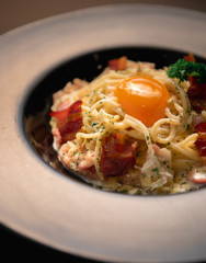 spaghetti carbonara egg On a black plate spaghetti carbonara egg  On a black background