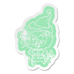 cartoon distressed sticker of a roaring lion with gift wearing santa hat