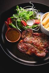 Pork steak, black pepper sauce  On a black plate. Pork steak, black pepper sauce  On a black background