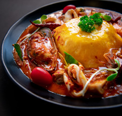 Thai Food Recipe .Thick rice soup, Tom Yum sauce, seafood .Thick egg rice On a black plate 