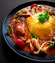 Thai Food Recipe .Thick rice soup, Tom Yum sauce, seafood .Thick egg rice On a black plate 