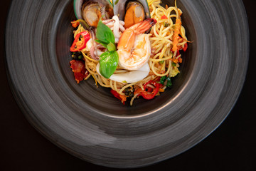 Thai Food Recipe Stir Fried Spaghetti with Seafood On a black plate.Spaghetti with Seafood On a black plate.
