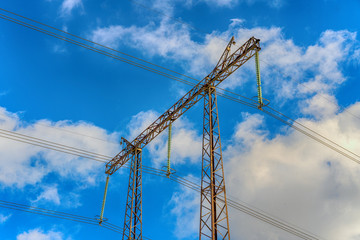 Pylons of high-voltage power lines and a blue sky with clouds