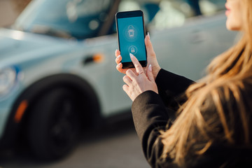 Woman using Smartphone near the car. Mobile phone apps for car owners concept.