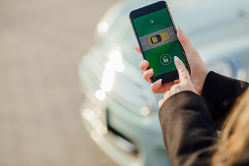Woman using Smartphone near the car. Mobile phone apps for car owners concept.