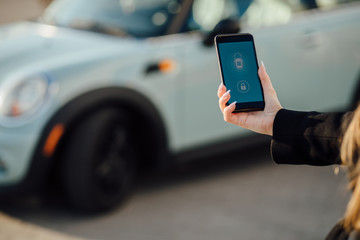 Woman using Smartphone near the car. Mobile phone apps for car owners concept.