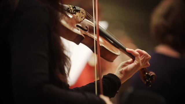 Close up footage of a person performing on a violin during a concert.