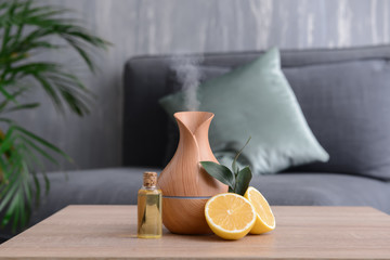 Aroma oil diffuser and citrus fruit on table in room