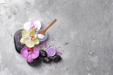 Fototapeta na wymiar Spa stones, orchid flowers and sea salt on grey background