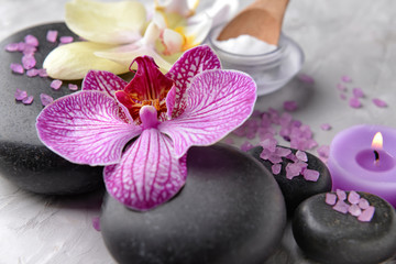 Spa stones and orchid flower on grey background, closeup