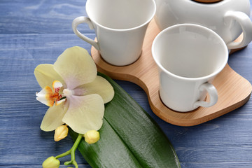Empty cups and beautiful orchid flower on wooden table