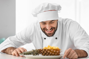 Male confectioner with tasty fruit dessert in kitchen