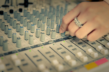 finger of engineer or music producer controlling sound recording studio mixing desk