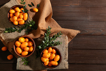 Bowls with delicious kumquat fruit on table