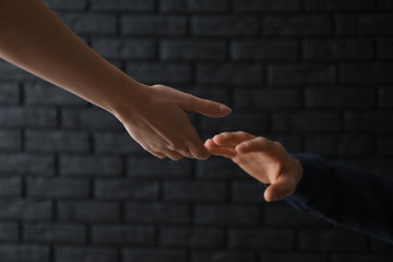 Woman giving hand to depressed man against dark background. Suicide prevention concept - obrazy, fototapety, plakaty