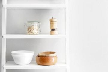 Fototapeta na wymiar Shelves with kitchenware near white wall