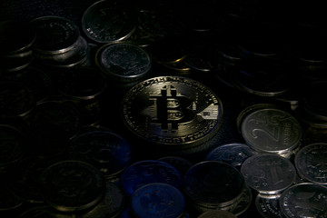 gold coin bitcoin surrounded by other coins in a beam of light with a blue glare. on black