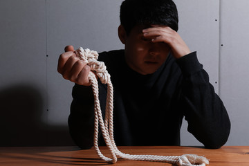 Depressed man with rope thinking about suicide at home