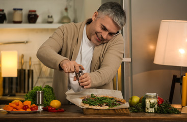 Mature man cooking tasty pizza at home