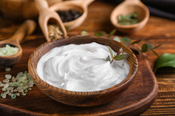 Plate with natural cream on wooden board, closeup