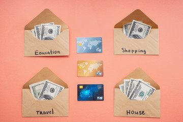 Envelopes with money for different needs and credit cards on color background. Concept of savings