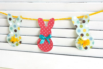 Easter decor home garland of paper colored hares and tails of yarn on a wooden white latticed wall...