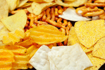 Mix of snacks : pretzels , crackers , chips  and nachos on the table