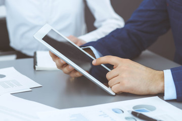 Businessman using tablet at meeting, closeup of hands. Business operations concept