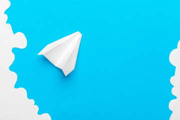 Flying paper plane in the clouds on a blue background. Concept of flight, travel, transfer