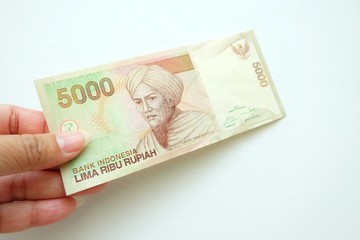  Woman hand holding  Indonesia banknote on white background. 